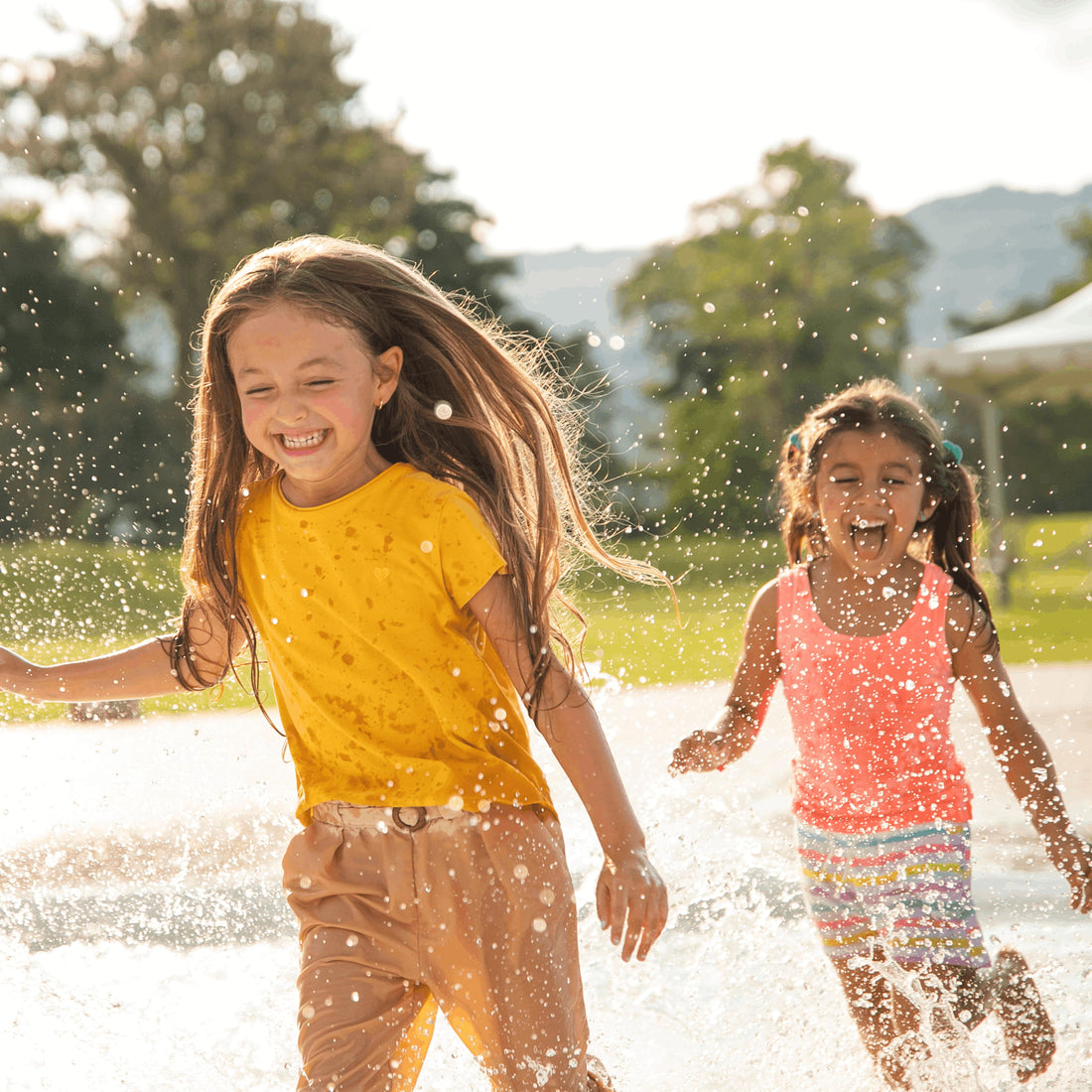 two girls running through a splash pad